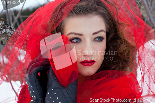 Image of Beautiful woman with dark hair and red lips in white snow