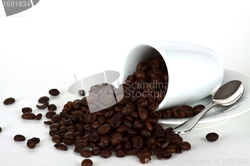 Image of white coffe cup with coffe beans and a silver spoon