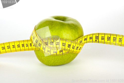 Image of fresh green apple with yellow measure tape 