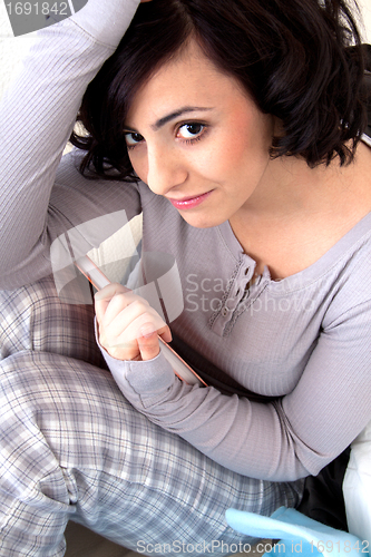 Image of beautiful woman is sitting on the sofa an reading a book 