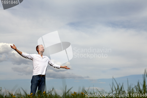 Image of man is standing outside in spring with arms wide open and breathing