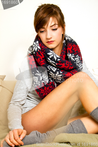Image of young beautiful woman is sitting an a sofa and relaxing
