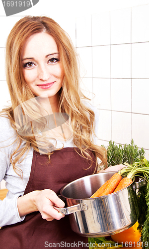 Image of young beautiful housewife is cooking with fresh vegetables