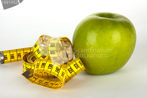 Image of fresh green apple with yellow measure tape 