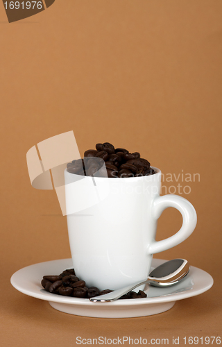 Image of white coffe cup with coffe beans and a silver spoon