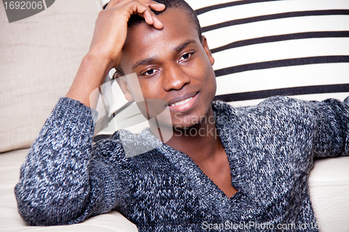 Image of dark-skinned man sitting on the floor in front of the couch