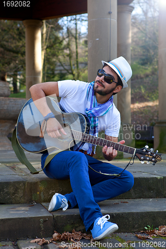 Image of young man is playing a guitar and singing