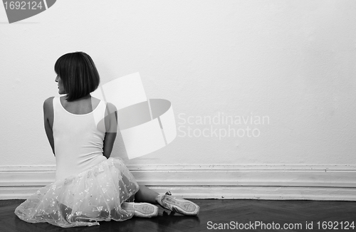 Image of beautiful ballerina is sitting on the floor in black and white