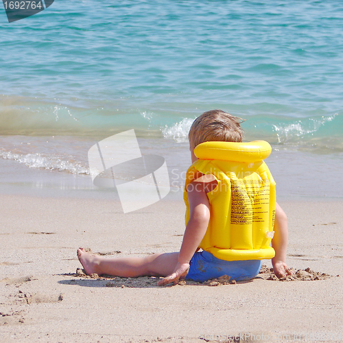 Image of Liitle boy on the beach in lifejacket