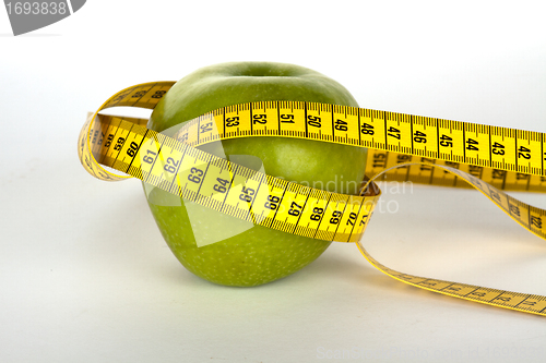 Image of fresh green apple with yellow measure tape 