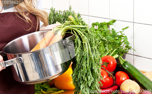 Image of young beautiful housewife is cooking with fresh vegetables