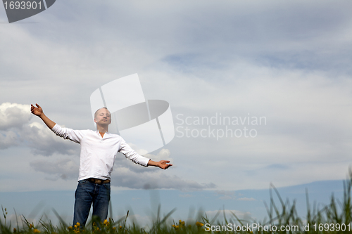 Image of man is standing outside in spring with arms wide open and breathing
