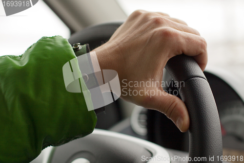 Image of hand on wheel man is driving a car