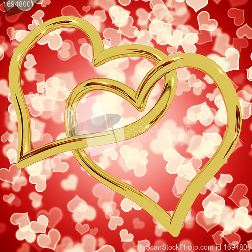 Image of Gold Heart Shaped Rings On Red Bokeh Representing Love And Roman