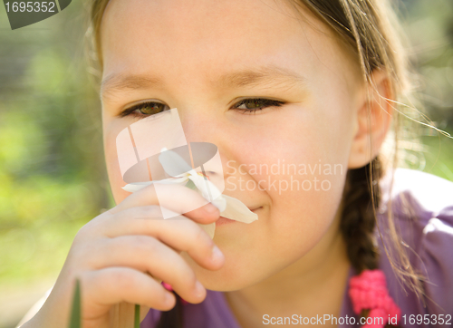 Image of Portrait of a cute little girl smelling flowers