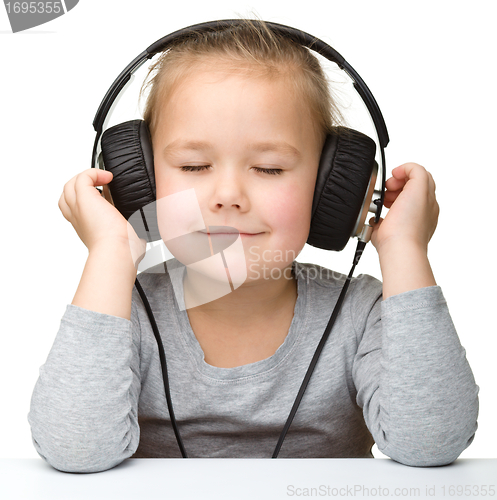Image of Cute little girl enjoying music using headphones