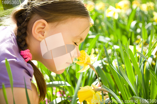 Image of Portrait of a cute little girl smelling flowers