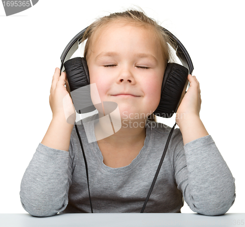 Image of Cute little girl enjoying music using headphones