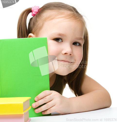 Image of Cute little girl is hiding behind a book
