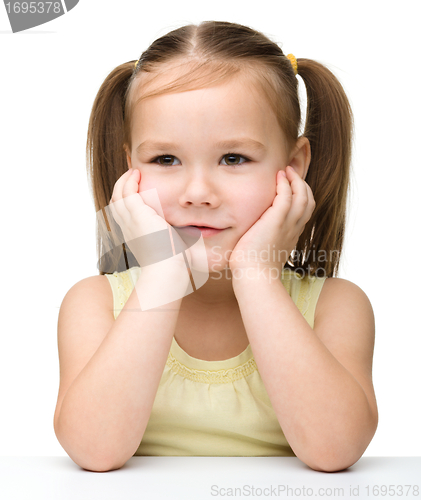 Image of Happy little girl sits at a table