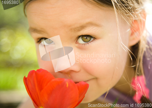 Image of Portrait of a cute little girl smelling flowers