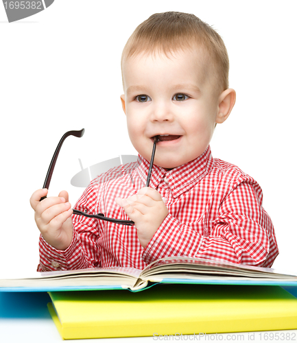 Image of Little child play with book and glasses