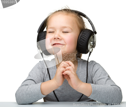 Image of Cute little girl enjoying music using headphones