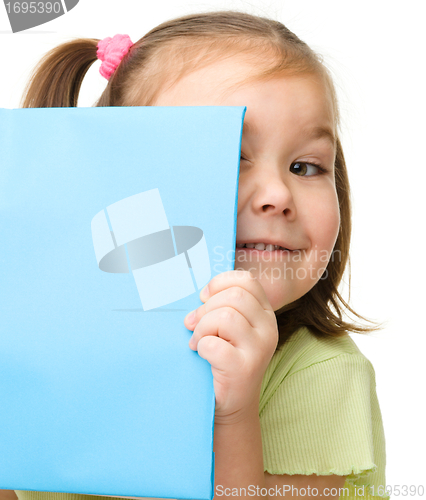 Image of Cute little girl is hiding behind a book