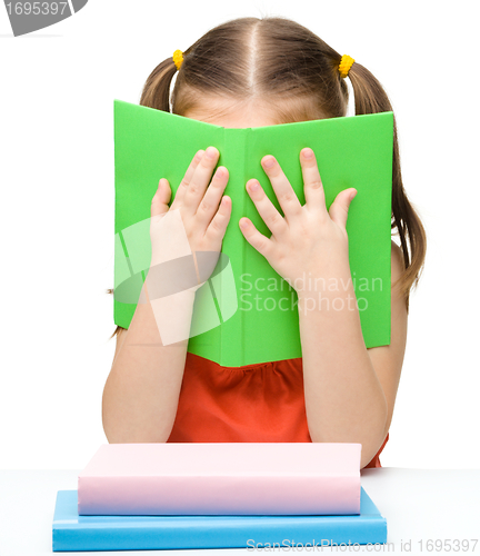 Image of Cute little girl is hiding behind a book