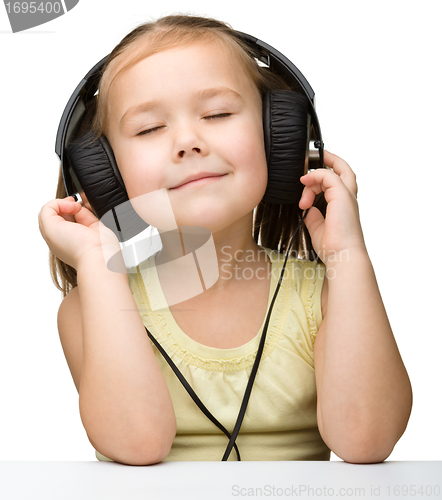 Image of Cute little girl enjoying music using headphones