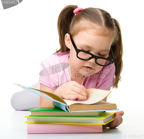 Image of Cute little girl reads a book wearing glasses
