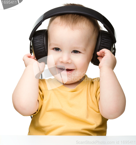 Image of Cute little boy enjoying music using headphones
