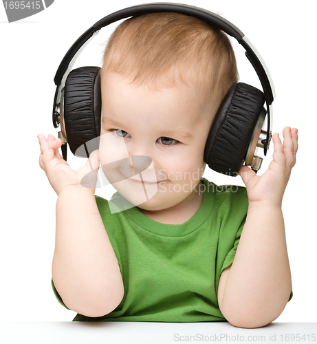 Image of Cute little boy enjoying music using headphones