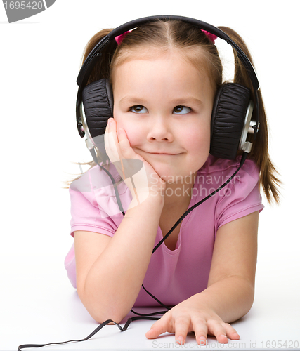 Image of Cute little girl enjoying music using headphones