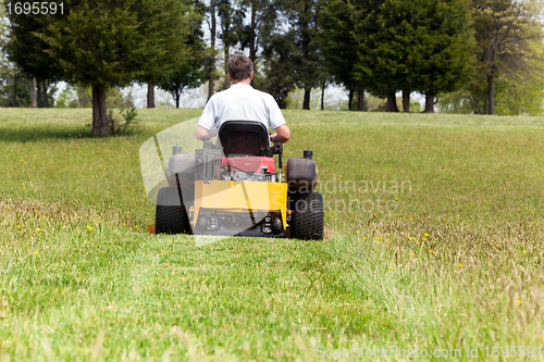 Image of Senior man on zero turn lawn mower on turf