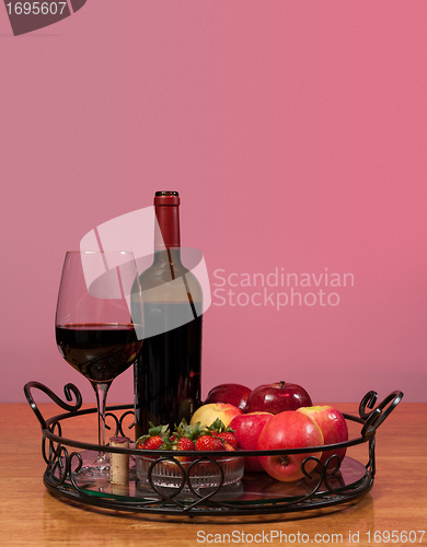 Image of Red wine bottle and fruit with glass