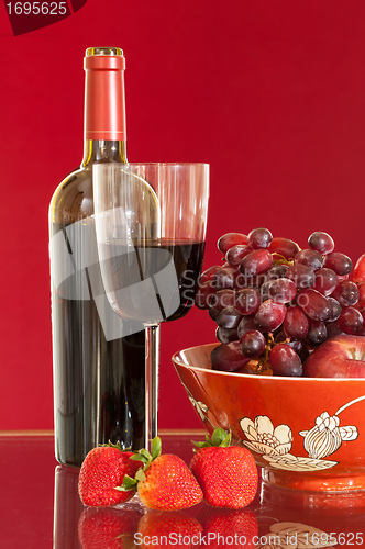 Image of Red wine bottle and fruit with glass