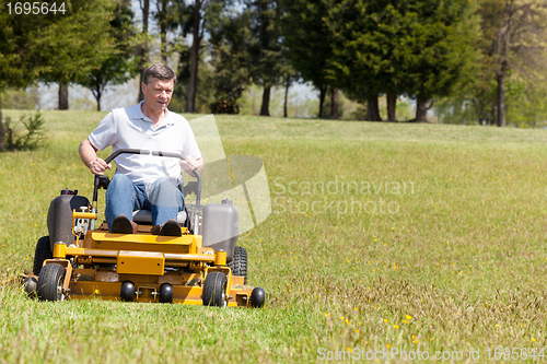 Image of Senior man on zero turn lawn mower on turf