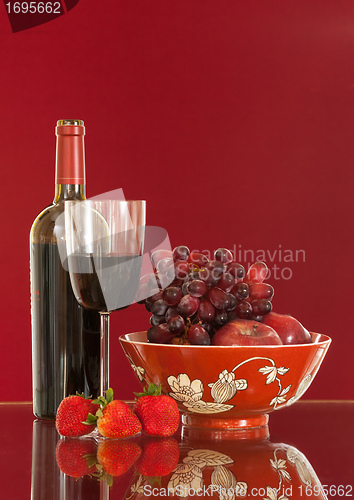 Image of Red wine bottle and fruit with glass