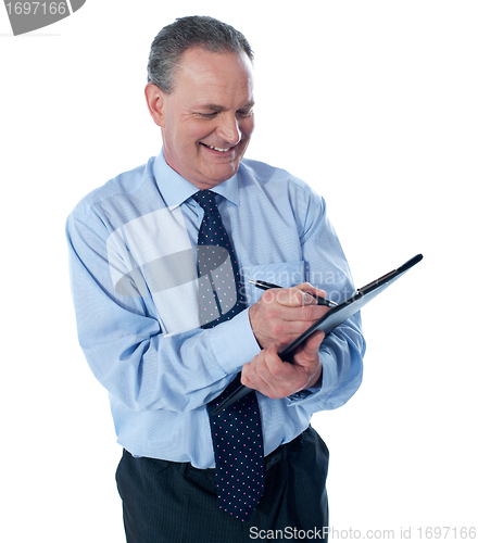 Image of Smiling businessman writing on clipboard
