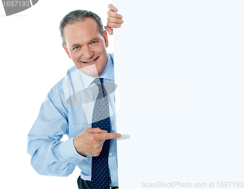 Image of Businessman peeking behind a whiteboard