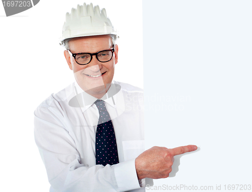 Image of Senior man in white construction helmet holding placard