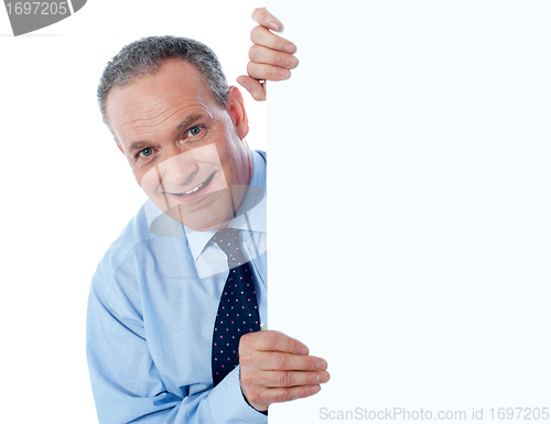 Image of Man peeking behind empty white billboard