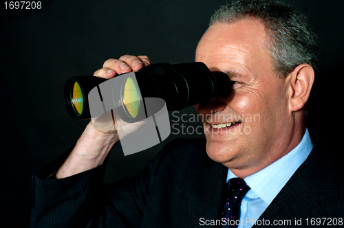 Image of Aged executive monitoring through binoculars