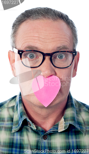 Image of Surprised aged male with paper heart over his mouth