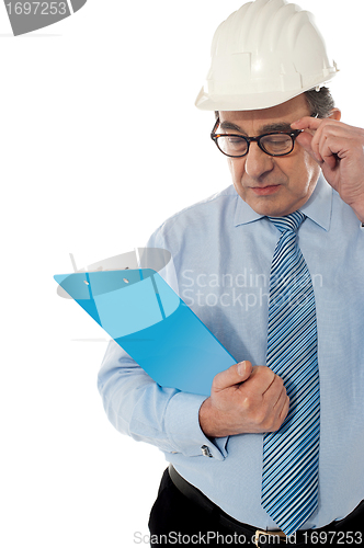 Image of Experienced achitect in hardhat studying files. Isolated on white