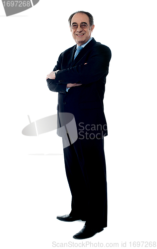 Image of Smiling senior executive posing with folded arms