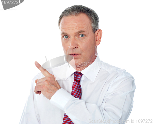 Image of Portrait of senior businessman pointing backwards