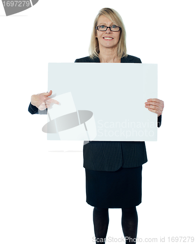 Image of Corporate woman pointing towards blank billboard