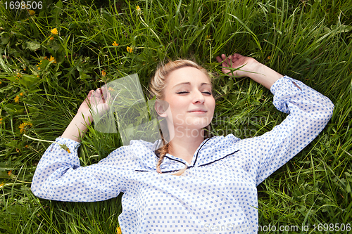 Image of young woman lying in green gras happy